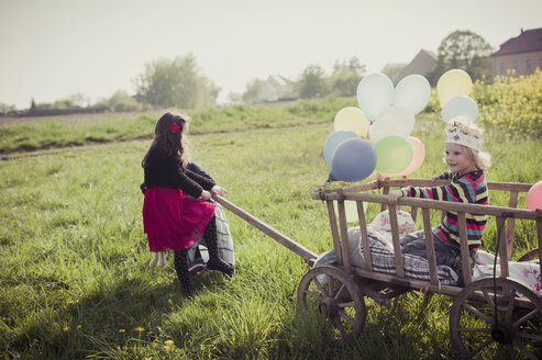 Drei Kinder unterwegs mit Holzwagen und Luftballons - MJF001115