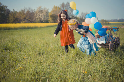 Drei Kinder unterwegs mit Holzwagen und Luftballons - MJF001117