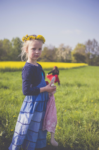 Porträt eines kleinen Mädchens mit Stofftier vor einem Rapsfeld, lizenzfreies Stockfoto