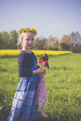 Porträt eines kleinen Mädchens mit Stofftier vor einem Rapsfeld - MJF001118