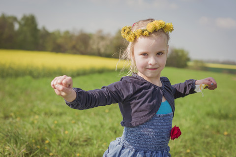 Kleines Mädchen mit ausgestreckten Armen auf einer Wiese stehend, lizenzfreies Stockfoto