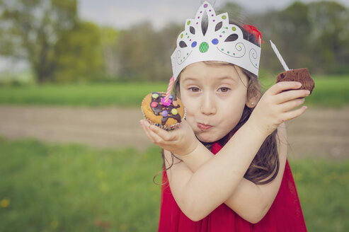 Portrait of little girl with birthday muffins making face - MJF001135