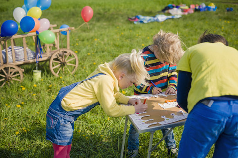 Kinder malen Papierkronen für eine Geburtstagsfeier, lizenzfreies Stockfoto