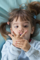 Porträt eines kleinen Mädchens, das auf einem Bohnensack liegt und mit den Fingern zählt, Ansicht von oben - LVF001158