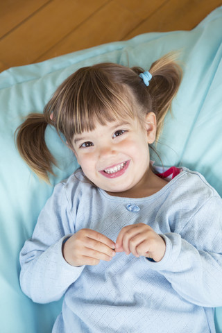 Portrait of smiling little girl lying on bean bag, elevated view stock photo