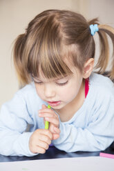 Porträt eines kleinen Mädchens mit Wachsmalkreide, das sein Bild betrachtet - LVF001168