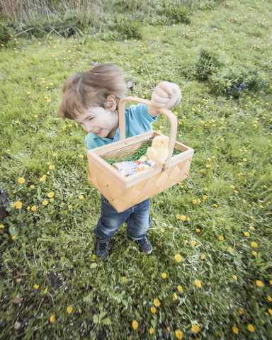 Glücklicher kleiner Junge mit Korb, der im Garten tanzt, lizenzfreies Stockfoto