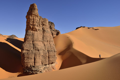Algerien, Tassili n' Ajjer, Tadrart, Sahara, Tassili n' Ajjer National Park, Blick auf Sanddünen und Felsen von Moul Nag mit Menschen im Hintergrund, lizenzfreies Stockfoto