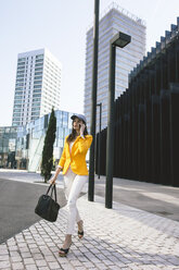 Spain,Catalunya, Barcelona, young modern woman with yellow jacket on the move - EBSF000193