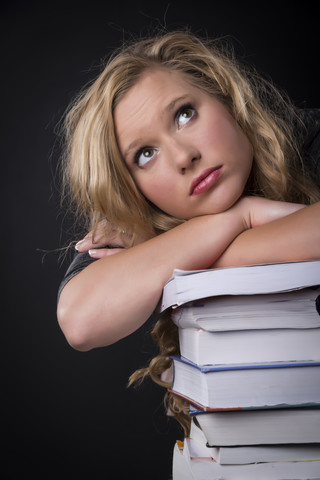 Porträt einer jungen Frau, die sich auf einen Bücherstapel stützt, lizenzfreies Stockfoto