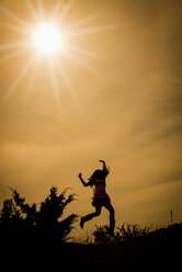 Silhouette einer springenden Frau im Gegenlicht - ABAF001327