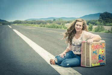 Young woman hitchhiking at empty street - ABAF001339