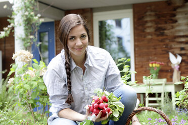 Junge Frau mit roten Radieschen im Gemüsegarten - SGF000635