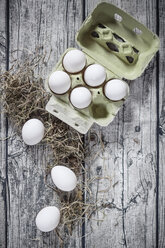 Eierkarton mit weißen Eiern und Heu auf Holzbrettern, Ansicht von oben - SBDF000801