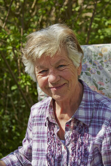 Porträt einer lächelnden älteren Frau im Garten - AKF000367