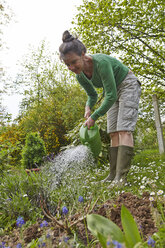 Ältere Frau gießt Blumen im Garten - AKF000389