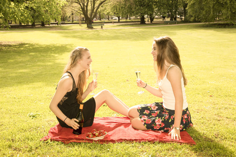 Zwei junge Freundinnen feiern Geburtstag im Park, lizenzfreies Stockfoto