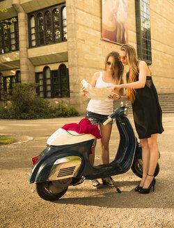 Two young woman with road map and Vespa - FCF000179