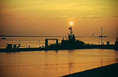 Germany, Bremen, Bremerhaven, Harbour tug on jetty, Weser river at sunset - HOHF000772