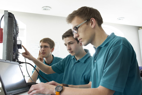 Drei Elektronik-Lehrlinge testen in der Werkstatt, lizenzfreies Stockfoto