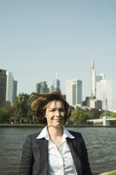 Deutschland, Hessen, Frankfurt, Porträt einer lächelnden Geschäftsfrau vor einer Skyline - UUF000465