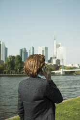 Deutschland, Hessen, Frankfurt, Geschäftsfrau beim Telefonieren mit Smartphone vor Skyline, Rückansicht - UUF000466