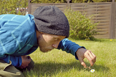 Mann schneidet Gänseblümchen mit Miniaturschere - HACF000110