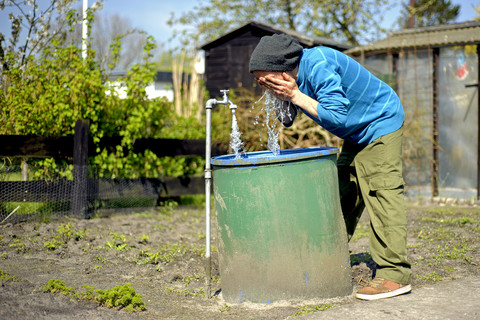 Mann wäscht sich im Garten, lizenzfreies Stockfoto