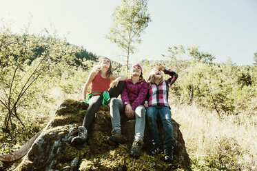 Drei Mädchen auf einem Felsen in der Natur sitzend - HHF004808