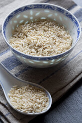 Schale und Porzellanlöffel mit braunem Bio-Reis auf Tuch und Schiefer - SARF000588