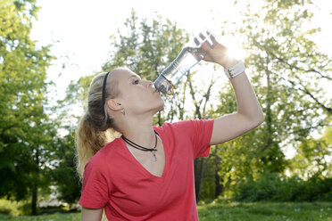 Porträt einer jungen Frau, die Wasser aus einer Flasche trinkt - BFRF000411