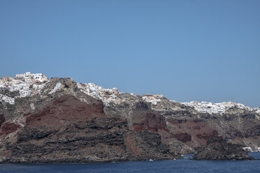Griechenland, Santorin, griechische Flagge mit Fira im Hintergrund von der  Caldera aus gesehen, lizenzfreies Stockfoto