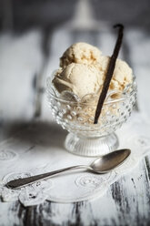 Glass of vanilla ice cream with vanilla pod and spoon on wooden table - SBDF000879