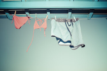 Bikini und Badehose hängen auf der Wäscheleine unter dem Dach - KRPF000455