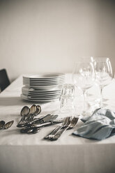 Table with stack of plates, wine and water glasses and silver cutlery - SBDF000886