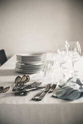 Tisch mit Stapel von Tellern, Wein- und Wassergläsern und Silberbesteck - SBDF000886