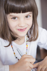 Porträt eines lächelnden kleinen Mädchens, das mit Wachsmalkreide malt - LVF001218