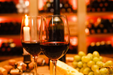 Zwei Gläser Rotwein, eine Kerze, Weintrauben und eine Flasche im privaten Weinkeller - JTF000549