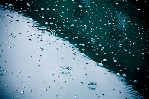 Raindrops falling on puddle, partial view stock photo