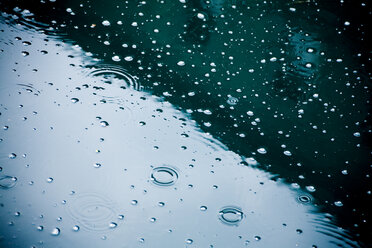 Regentropfen fallen auf Pfütze, Teilansicht - DISF000832