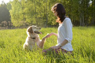 Golden Retriever gibt junger Frau eine Pfote - BFRF000429