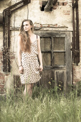 Junge Frau steht vor einem alten Gartenhaus - FCF000207