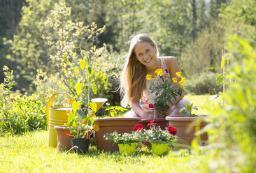 Porträt eines lächelnden Teenagers beim Umtopfen von Pflanzen im Garten - WWF003296