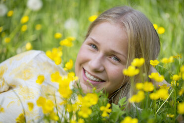 Porträt eines lächelnden Teenagers, der auf einer Blumenwiese liegt - WWF003308