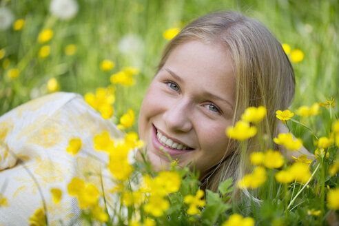 Portrait of smiling teenage girl lying on a flower meadow - WWF003308