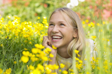 Porträt eines glücklichen Teenagers, der auf einer Blumenwiese liegt - WWF003309