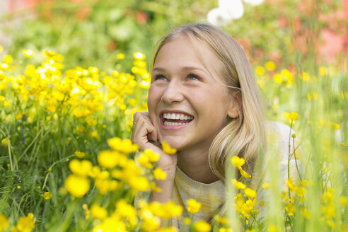 Portrait of happy teenage girl lying on a flower meadow - WWF003309