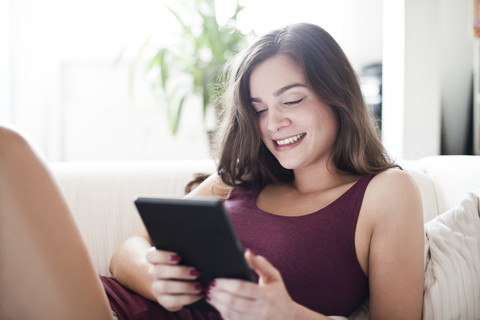 Porträt einer lächelnden jungen Frau mit Tablet-Computer zu Hause, lizenzfreies Stockfoto