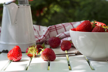 Schale mit Erdbeeren, Messer, Küchentuch und Glas auf weißem Holz - LVF001244