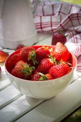 Schale mit Erdbeeren, Küchenhandtuch und Glas auf weißem Holz - LVF001245